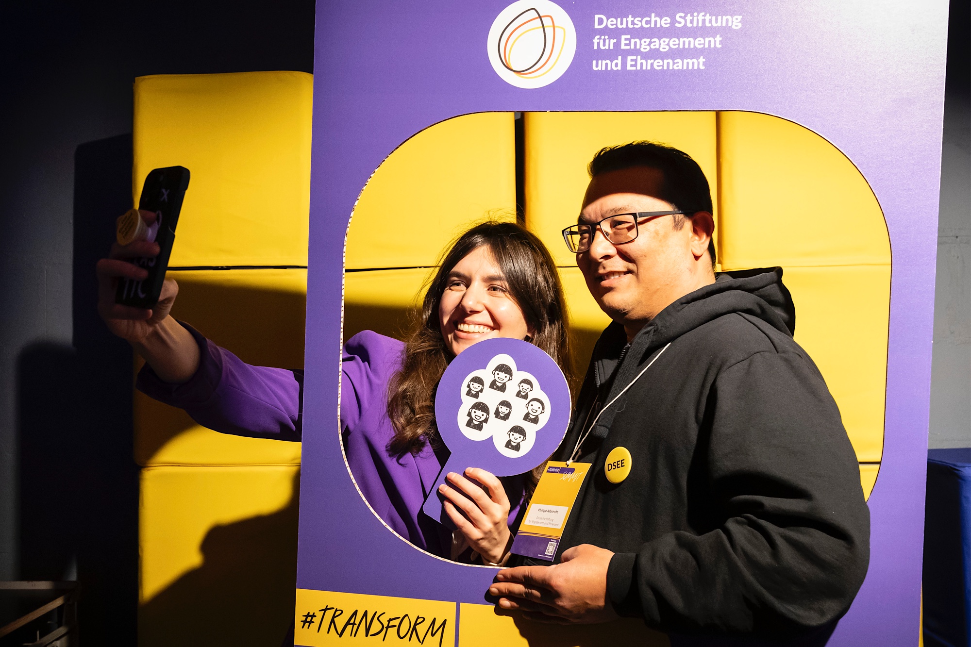 Zwei Teilnehmende des Summits machen ein Selfie in einem transform_d-Rahmen der DSEE