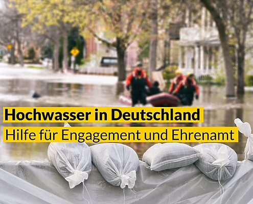 Foto von Sandsäcken als Damm bei einer überfluteten Straße. Text: Hochwasser in Deutschland – Hilfe für Engagement und Ehrenamt
