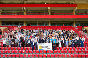 Gruppenbild auf der Stadiontribüne "An der alten Försterei" in Berlin mit den vielen engagierten Vertretern:innen der Preisträger des Machen!2024 Wettbewerbs.
