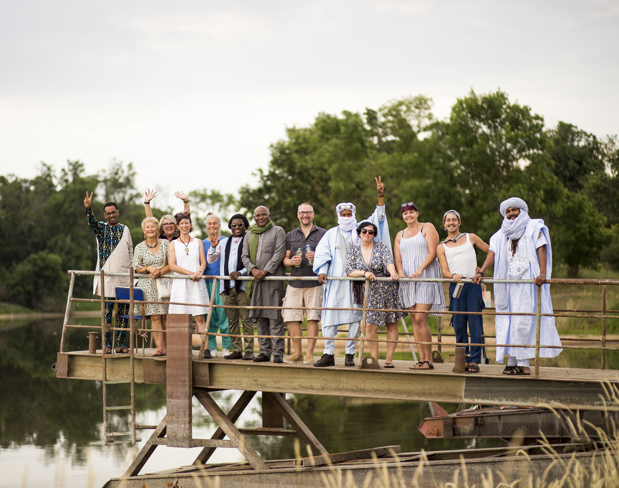 Mitglieder des ELa-Netzwerks "Wir am Wasser" aus Arken sttehen für ein Gruppenfoto auf einem Steg und winken