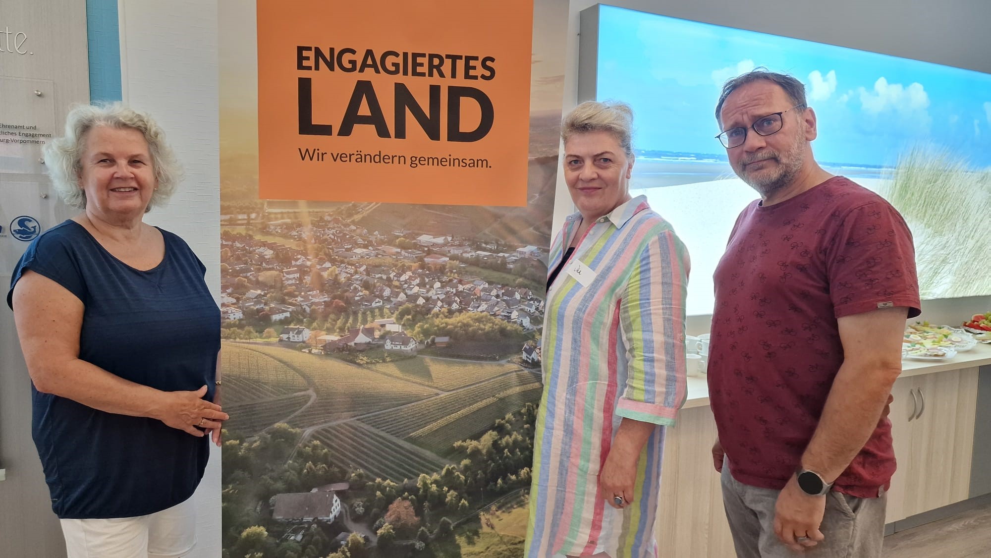 NF 4 - Bürger für Schwaan Drei Engagierte des Netzwerks Schwaan stehen vor einem ELa-Plakat